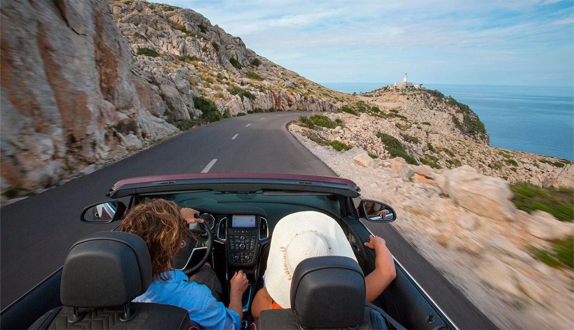 Couple driving on the coast in Spain in their convertable